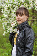 Beautiful young woman standing near the apple tree.