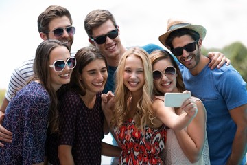 Happy friends taking a selfie near swimming pool on a sunny day