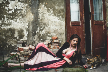 Gracious woman plays with a cat in front of an old door