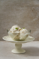 Rhubarb ice cream, beige background, glass bowl, white plateau.