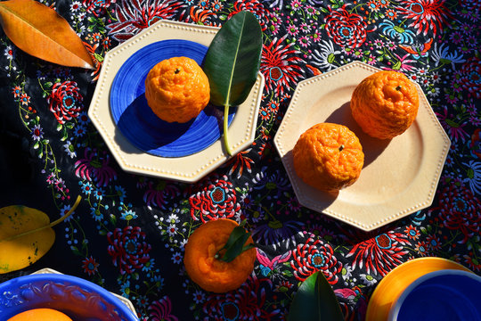 Oranges on the background of the Spanish fabric with ethnic dishes and natural sunlight