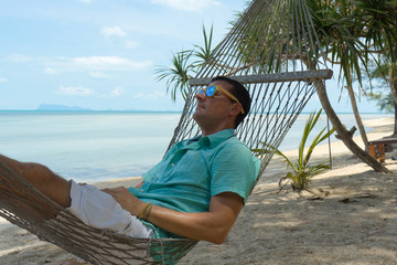 
The man in tropics and with the computer Young the beauty lying in a hammock with the laptop in the tropical resort