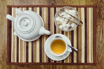 Top view of a cup of green tea, teapot and sugar bowl on a woode