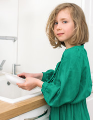 Little girl washing dishes in the kitchen.