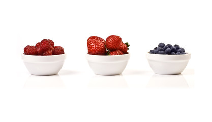 Three bowls with Raspberry, Strawberry and Blueberry isolated on white