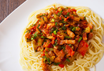 Spaghetti pasta with vegetables mix and bacon on white plate