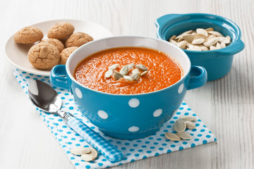 Pumpkin soup / Pumpkin soup with seeds and cookies in blue bowl on wooden background