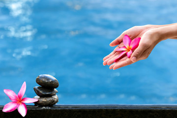 Hands holding Plumeria flower over water Spa concept