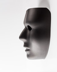 Black mask profile emerging from white background. Hidden identity concept.
