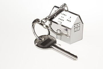 key with keychain in the form of a silver-colored house on a white background