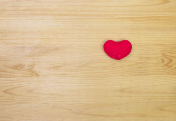 Red wool heart shape on wooden background