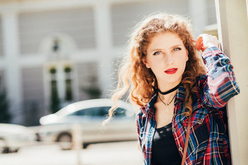 Beautiful woman with long blond curly hair in urban background 