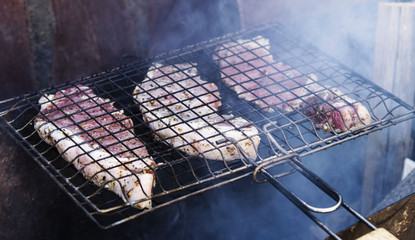 Roasting pork steaks on the grill over the burning coals of fire 