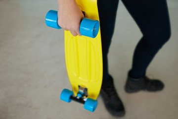 Closeup of a girl holding yellow longboard. 