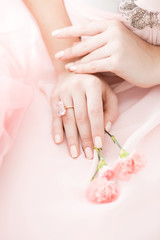 Pink Carnation flower in the hands of a girl on a pink background.