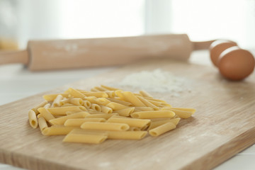 uncooked dried penne over cutting board with flour and eggs
