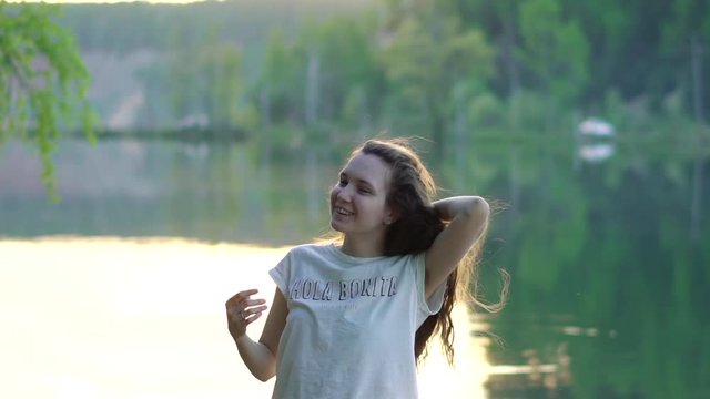 Красивая молодая девушка с кудрявыми волосами улыбается, портрет, модель, на берегу озера, на закате, замедленная съемка