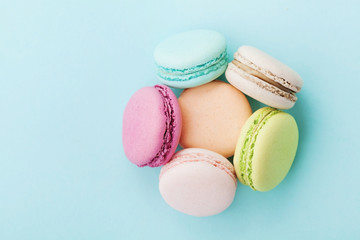 Cake macaron or macaroon on turquoise background from above, almond cookies, pastel colors, vintage card