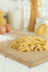 uncooked dried penne over cutting board with flour and eggs

