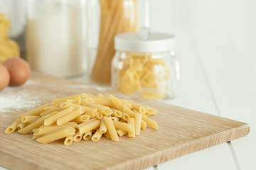 uncooked dried penne over cutting board with flour and eggs
