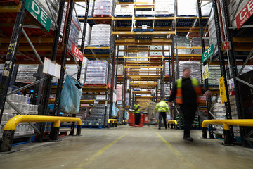 Fototapeta premium Staff in a warehouse move between storage racks, motion blur