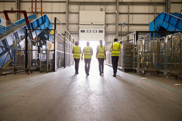 Four colleagues in reflective vests leaving a warehouse