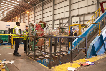Warehouse staff with a roll cage of cardboard for recycling