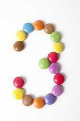 Il numero 3 formato da coloratissimi confetti di cioccolata.