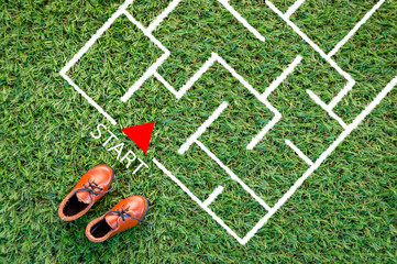 toy leather shoe on grass field and drawing of maze in the floor