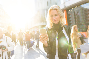 Blonde woman looking at smart phone in London