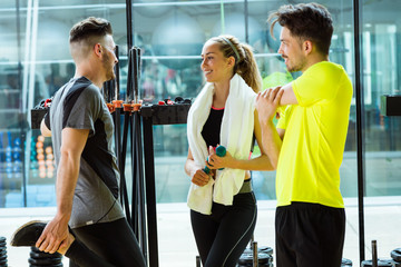 Group of sporty people relaxing and talking after class in gym.