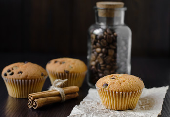 Muffins with coffee jar and cinnamon on dark background