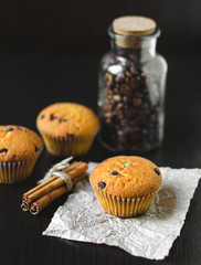 Muffins with coffee jar and cinnamon on dark background