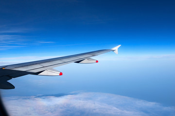 Wing of a Plane with Blue Sky and Clouds