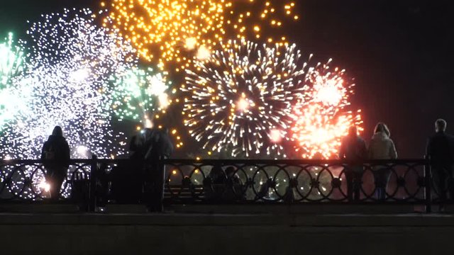 people standing on a bridge watching fireworks