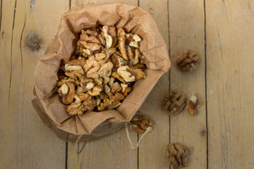 Грецкий орех в крафтовом пакете на деревянном фоне. Здоровое питание.