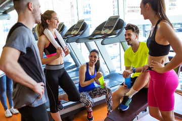 Group of sporty people relaxing and talking after class in gym.