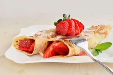 Crepes with strawberries sprinkled with powered sugar