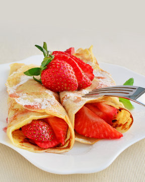 Crepes with strawberries sprinkled with powered sugar
