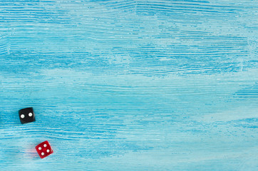 Red and black dice on old worn blue wooden background. Top view