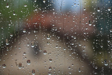 Rain drops on window with house and church in background