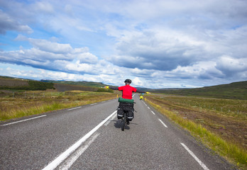 Obraz premium Biker rides on road at sunny summer day in Iceland