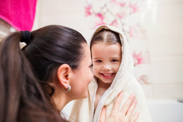 Mother drying daughter after taking bath, wrapped in towel