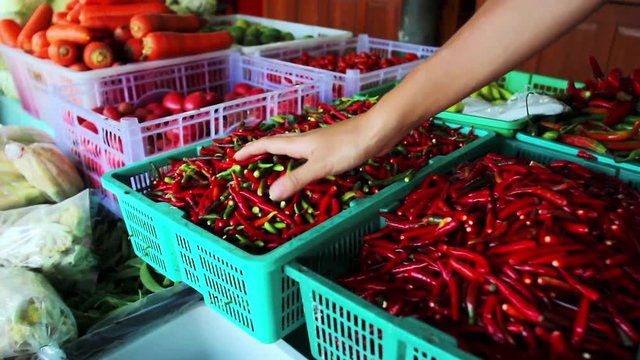 Female touching handful of chili pepper at food market in Thailand