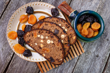 Sliced rye bread with prunes, dried apricots and hazelnut on old rustic table. Top view.
