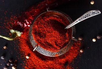 Old container for spices stuffed full of ground chili pepper. The photo in a dark key.