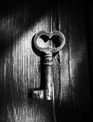 Rusty key on old wooden surface, black and white photo