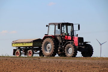 Obraz premium Red tractor with green trailer on a field