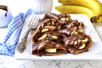 Chocolate pancakes with banana and chocolate sauce.