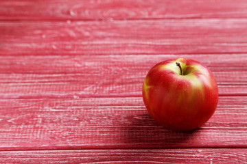 Ripe apple on a red wooden table